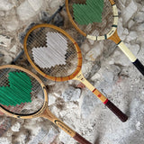 Three vintage tennis rackets on a textured stone surface