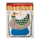 A decorative matchbox filled with wooden matches topped with red tips. The front of the box features a whimsical duck illustration in green, blue, black, and cream on a light beige background.