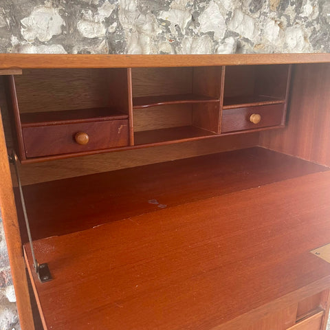 files/A_mid-century_modern_wooden_writing_desk_with_an_integrated_shelf_unit_featuring_two_small_drawers_with_round_knobs_set_against_a_stone-patterned_wall..jpg