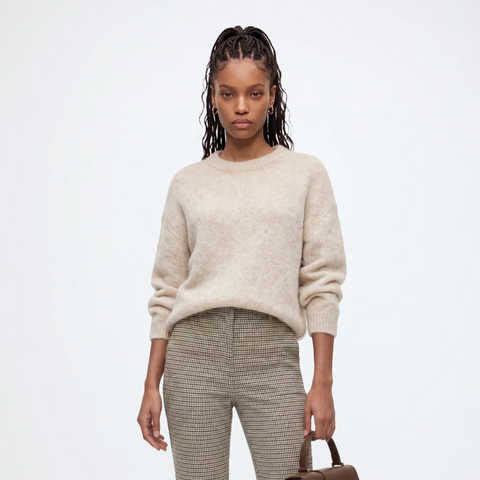 files/A_model_stands_against_a_light_gray_studio_background_wearing_a_cream_alpaca_knit_sweater_beige-and-gray_patterned_trousers_black_loafers_and_holding_a_brown_handbag..png