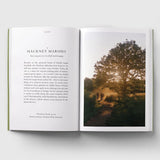 An open hardcover book laid flat on a light gray background, showing a printed page with text on the left and a landscape photograph of Hackney Marshes on the right.