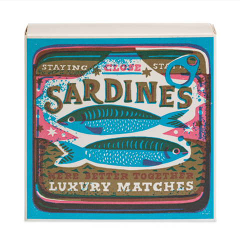 A box of matches with a vintage windmill press design featuring two sardines and the text 'SARDINES STAYING CLOSE MAKE LUXURY MATCHES'.