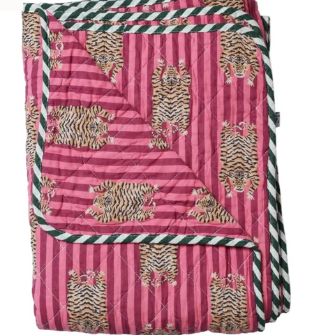 A folded quilted blanket featuring a pink and magenta striped pattern with printed tigers, bordered by dark green and white striped trim, shown on a white background.