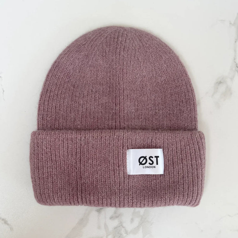 Mauve beanie with a white label on a marble surface