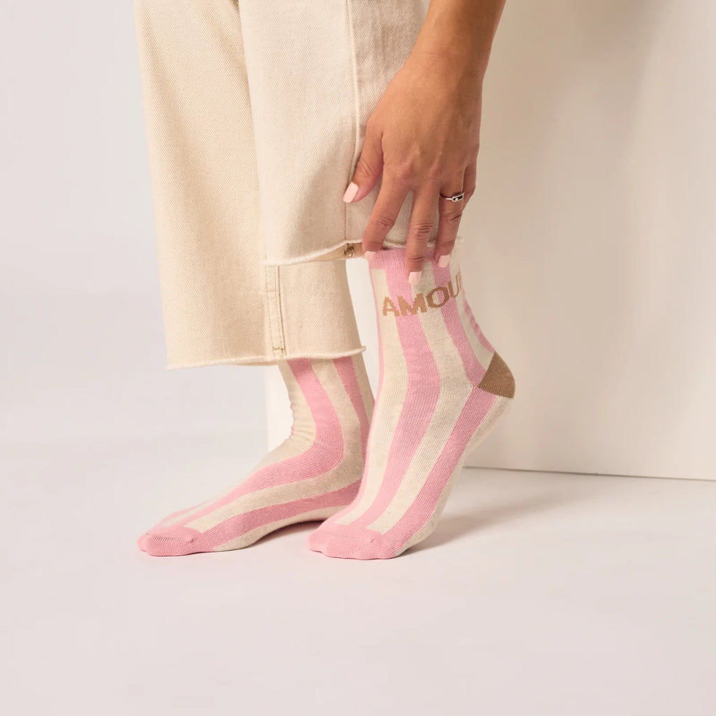 Pink and white striped socks with 'AMORE' text worn by a person.