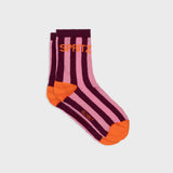 A pair of crew socks with vertical pink and dark purple stripes, bright orange heels, toes, and soles, featuring the brand name 'SPRITZ' in orange on the upper cuff and 'BLOOM' in orange on the foot.