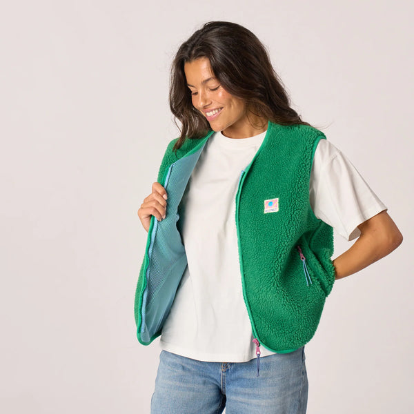 Woman wearing a green fleece vest with a visible brand logo on a plain background