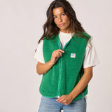 Woman wearing a green fleece vest with a visible brand logo on a plain background