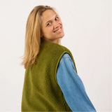 Person wearing a green fleece vest over a blue shirt on a white background
