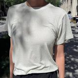Person wearing a light gray t-shirt and dark pants outdoors