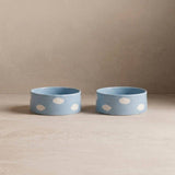 Two blue bowls with white polka dots on a beige surface and background
