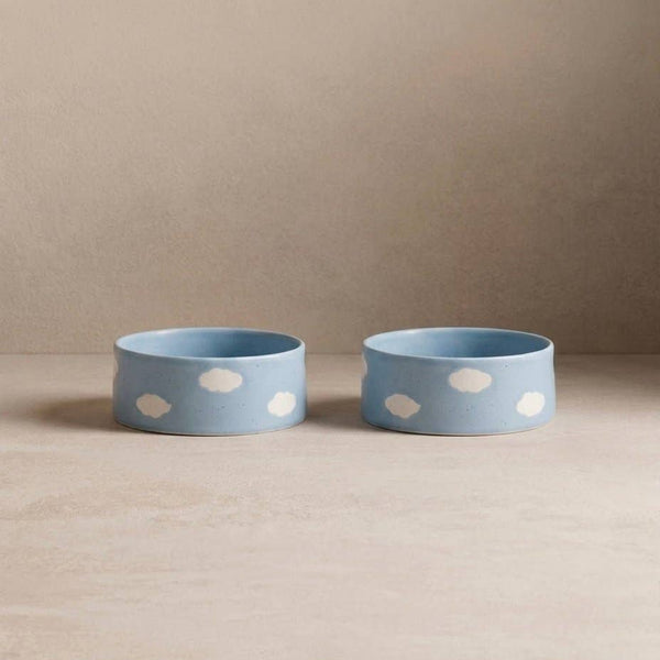 Two blue bowls with white polka dots on a beige surface and background