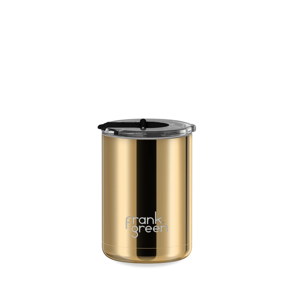 A gold stainless steel travel tumbler with a black lid and a black vertical accent stripe, featuring the 'frank green' logo near the bottom, set against a plain white background.