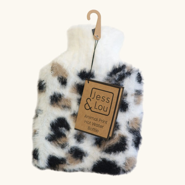 A plush faux-fur hot water bottle with an animal print pattern in black, beige, and white, hanging from a wooden hanger with a paper tag that reads 'Jess & Lou'.