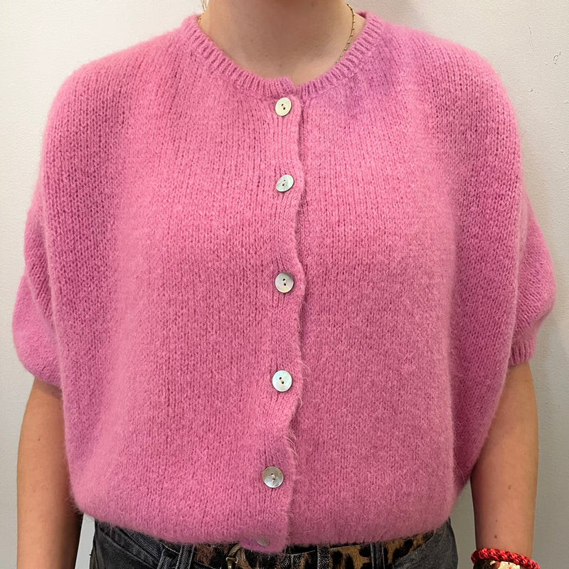 Pink knitted cardigan worn by a person on a plain background