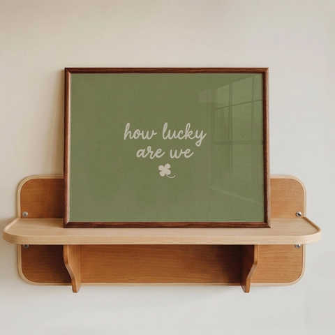 Dandy Prints ' How Lucky We Are' Framed Print Print is sage green with cursive white writing and a clover