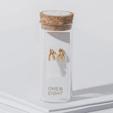 Gold earrings in a clear box with cork lid on a white background