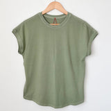 Green t-shirt on a wooden hanger against a white background