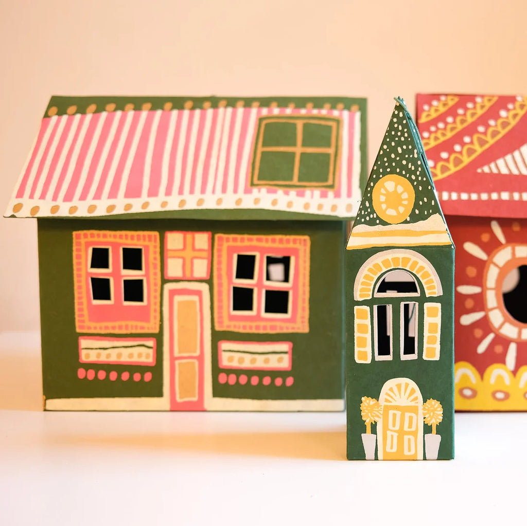Three hand-painted wooden house-shaped ornaments with colorful folk-art patterns, displayed on a light beige background.