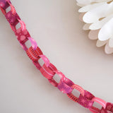 Close-up of a pink floral-patterned ribbon with white flowers in the background.