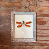 Framed artwork of a dragonfly on a wooden wall