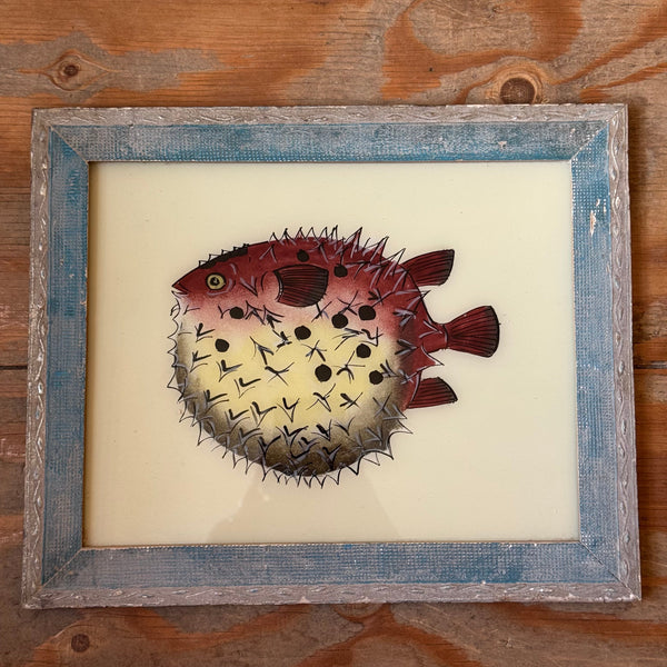 Framed artwork of a spiky fish on a wooden surface