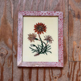 Framed artwork of flowers on a wooden surface