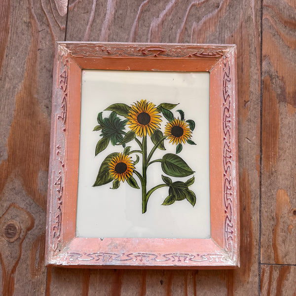 Framed embroidered artwork of sunflowers on a wooden surface