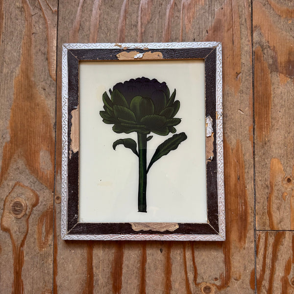 Framed pressed green flower on a wooden surface
