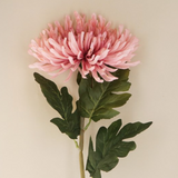 Pink artificial flower with green leaves on a beige background