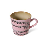 A pink ceramic mug with a textured, dripping dark gray pattern on the exterior and a warm beige interior, shown on a plain white background.