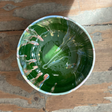 Green ceramic bowl with white interior on a wooden surface
