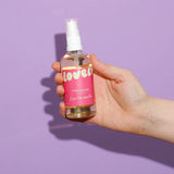 Hand holding a bottle of 'lovelys' vanilla sugar on a purple background