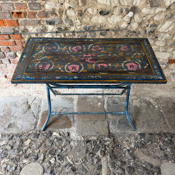 Decorative table with floral patterns on a stone pavement against a stone wall.