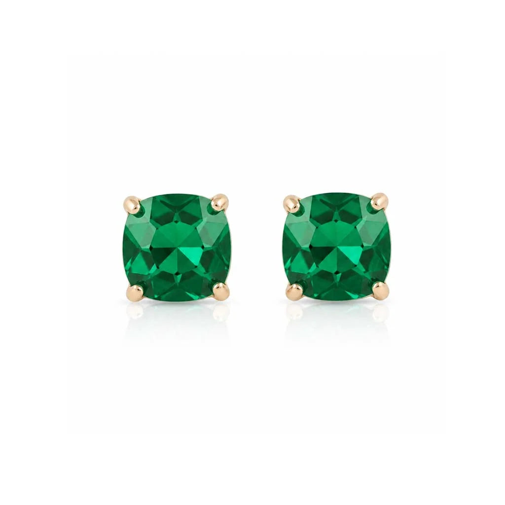 A pair of cushion-cut emerald green gemstone stud earrings in yellow gold four-prong settings, shown on a clean white background with a soft reflection below.