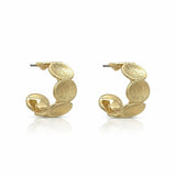 A pair of gold huggie hoop earrings with a textured, overlapping disc design, shown on a clean white background with a subtle reflection.