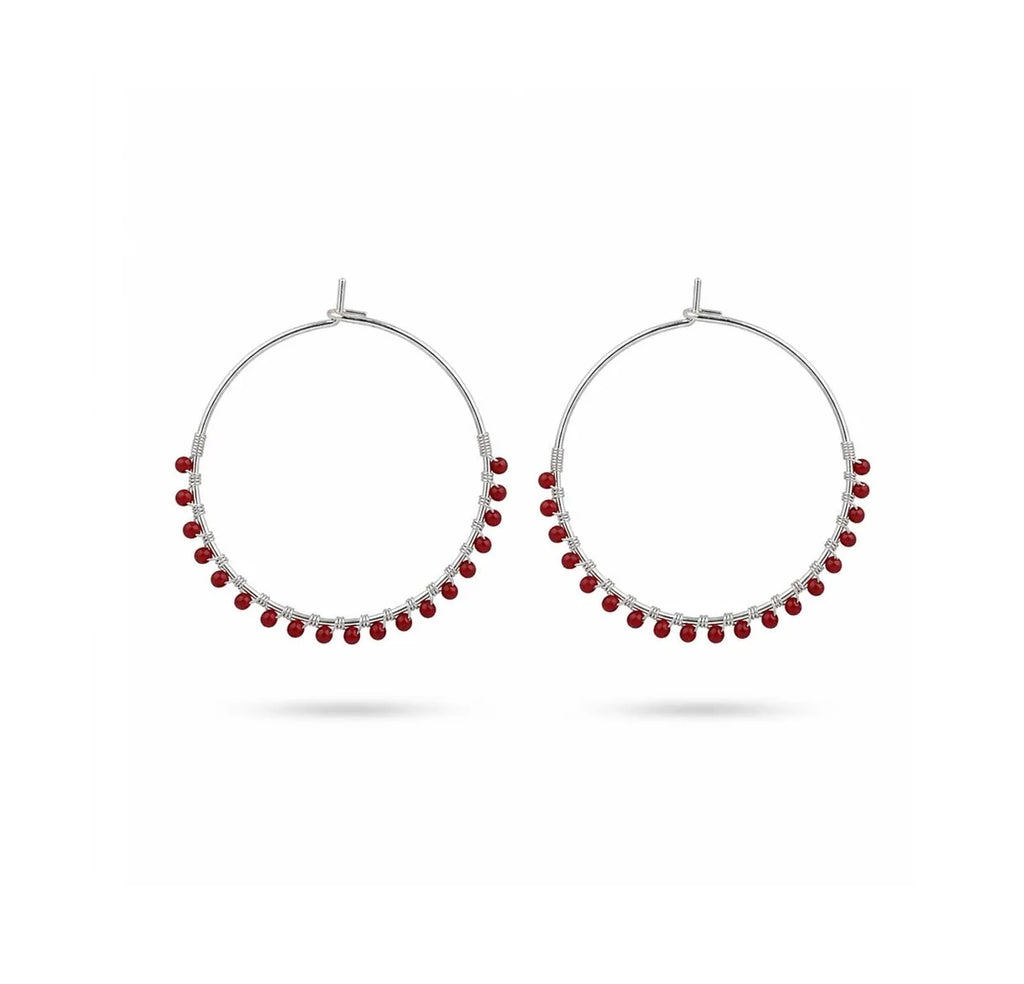 A pair of silver-tone hoop earrings with small red bead accents along the lower curve, displayed against a clean white background.