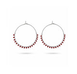 A pair of silver-tone hoop earrings with small red bead accents along the lower curve, displayed against a clean white background.