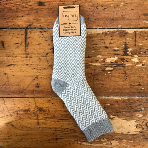 A pair of men's socks with a herringbone pattern, primarily grey and white, displayed on a wooden surface.