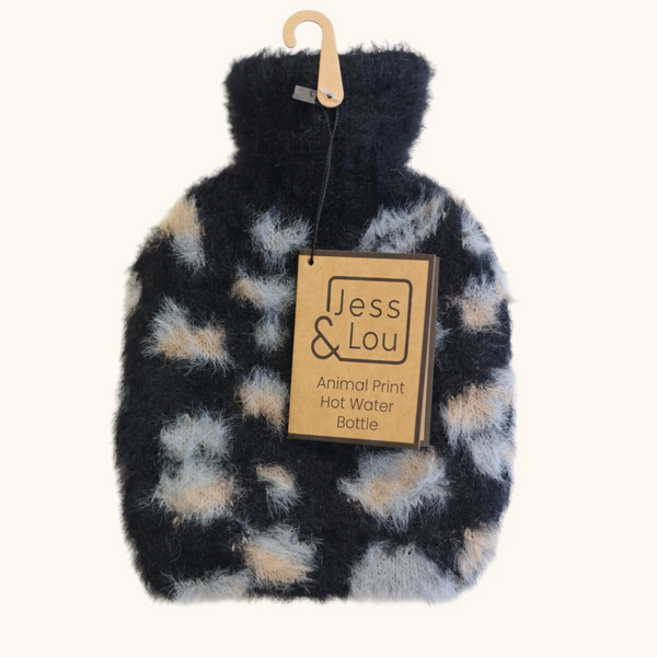Jess & Lou A plush faux-fur hot water bottle with an animal print pattern in black, beige, and gray, hanging from a wooden hanger with a paper brand tag that reads 'Jess & Lou'.