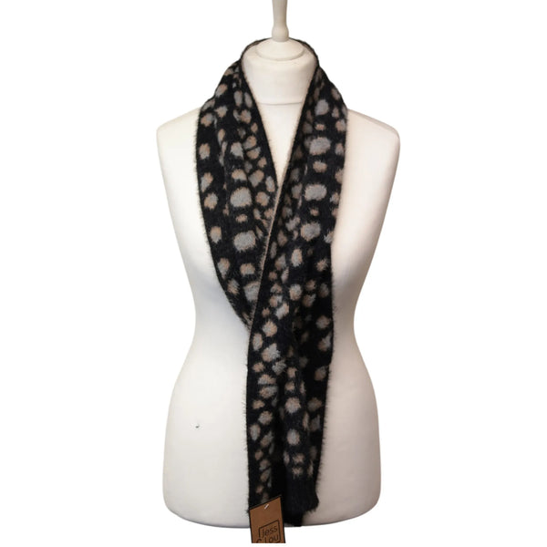 A black fuzzy scarf with a beige and gray spotted pattern, draped on a white mannequin torso against a white background.