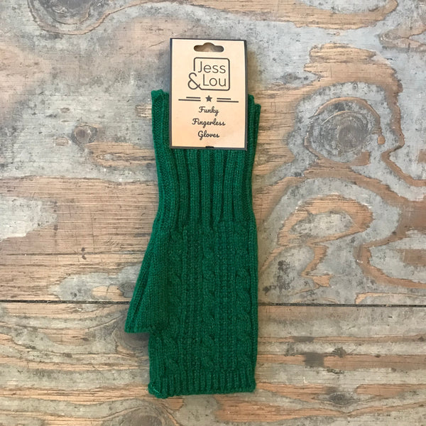 A pair of green cable knit fingerless gloves displayed on a wooden surface with branding tag attached.