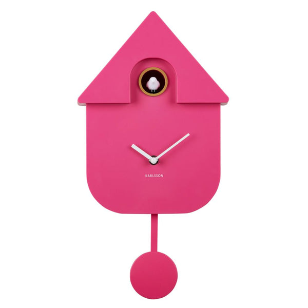 A bright pink house-shaped cuckoo clock with white hands and a small white bird window detail, shown against a plain white background. The brand name KARLSSON is printed below the clock face.