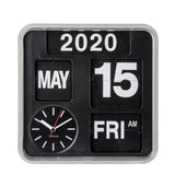 A square black flip-flap calendar clock with a silver-toned frame, displaying the year 2020, the date 15, the month MAY, the day FRI, and AM. A circular black dial with white hands and a red second hand is visible in the lower left.