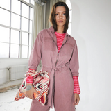 Lollys Laundry IrieLL Blouse Pink Woman wearing a pink jumpsuit with a striped shirt underneath, holding a patterned bag indoors.