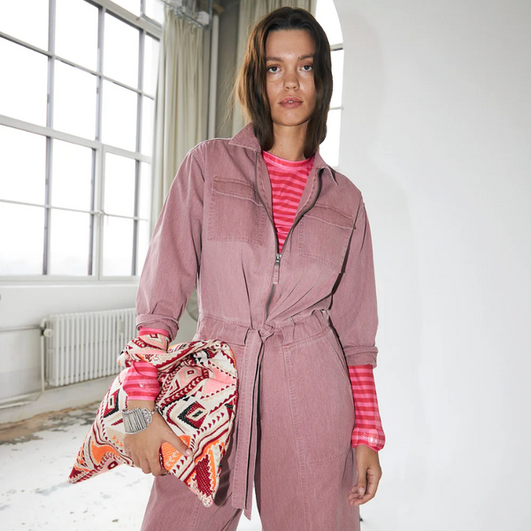 Lollys Laundry IrieLL Blouse Pink Woman wearing a pink jumpsuit with a striped shirt underneath, holding a patterned bag indoors.