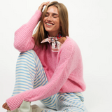 Woman wearing a Lollys Laundry IsoldeLL Knit Jumper and striped pants sitting on a white floor with inset images of the sweater.