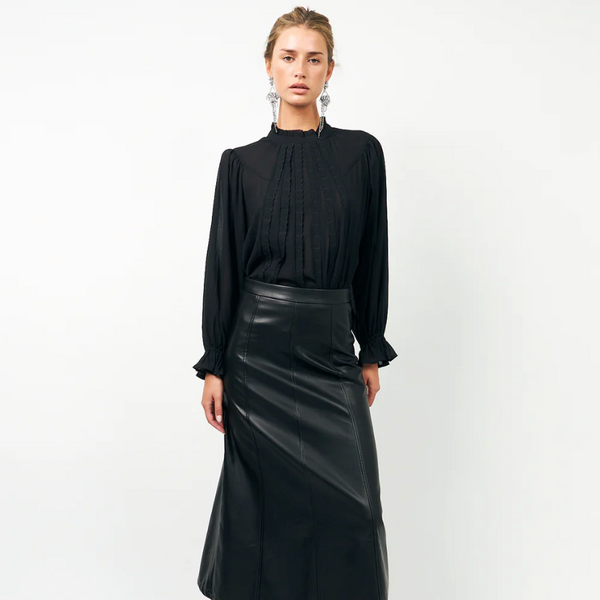 Woman wearing a black Lollys Laundry PresleyLL Shirt blouse and black leather skirt on a white background