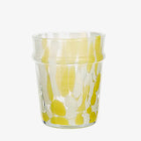 Clear glass tumbler with yellow and white abstract pattern on a white background