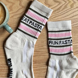 Two socks with text on a wooden surface next to a mug of coffee.